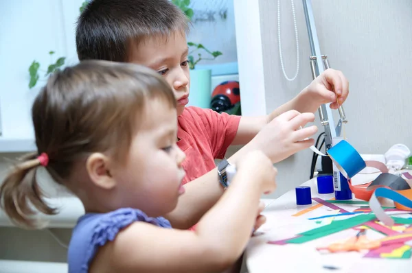 Boy and girl making craft with paper with glue — Stock Photo, Image