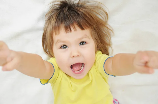 Feliz engraçado menina com as mãos para cima deitado na cama — Fotografia de Stock