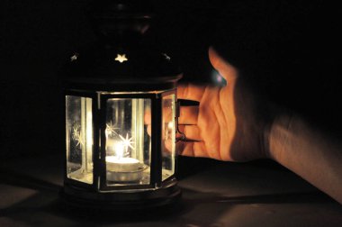 Karanlıkta fener mum ışığı ile aydınlatılan el