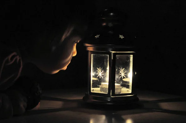 Маленькая девочка смотрит на свечи в фонаре, высокий iso — стоковое фото