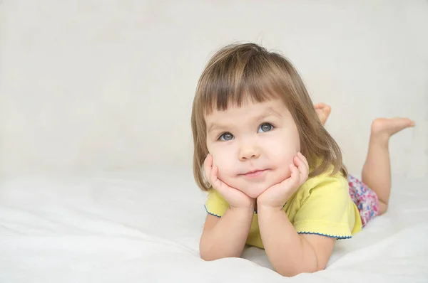 Marzy dziewczynka leżąc na łóżku uśmiechający się zadowolony na białym tle na białym tle — Zdjęcie stockowe