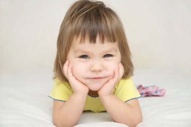 Çocuk portre tatlı, şirin yanakları etkileyici olumlu duygusal yüz izole yatak izole, mutlu çocukluk konsepti üzerinde yalan ile mutlu bir çocuk gülümseyen