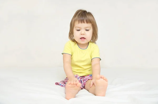 Kleines Mädchen sitzt isoliert auf dem Bett — Stockfoto