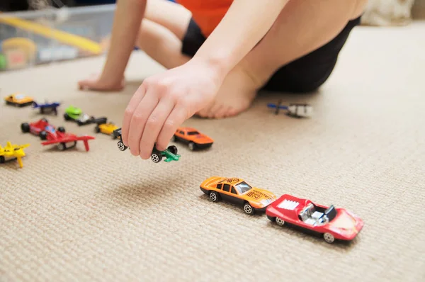 Niño jugando con la colección de coches en la alfombra. Transporte, avión, avión y helicóptero juguetes para niños, modelos en miniatura. Muchos coches para niños pequeños . — Foto de Stock