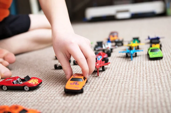 Niño jugando con la colección de coches en la alfombra. Transporte, avión, avión y helicóptero juguetes para niños, modelos en miniatura. Muchos coches para niños pequeños . — Foto de Stock