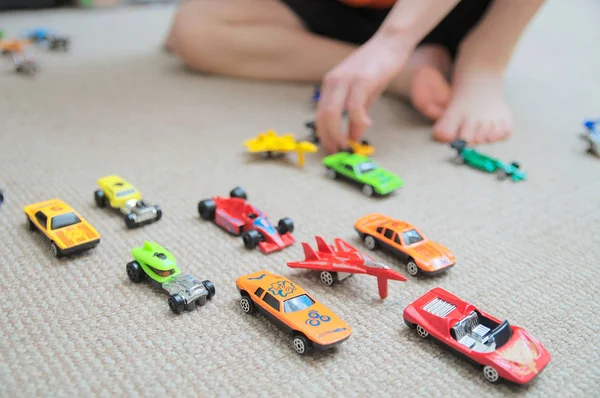 Jongen spelen met auto collectie op tapijt. Kind hand spelen. Vervoer, vliegtuig, vliegtuig en helikopter speelgoed voor kinderen, miniatuurmodellen. Veel auto's voor jongetjes. Rechtenvrije Stockfoto's