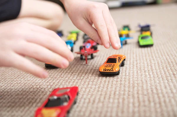 Jongen spelen met auto collectie op tapijt. Kind hand spelen. Vervoer, vliegtuig, vliegtuig en helikopter speelgoed voor kinderen, miniatuurmodellen. Veel auto's voor jongetjes. Stockafbeelding