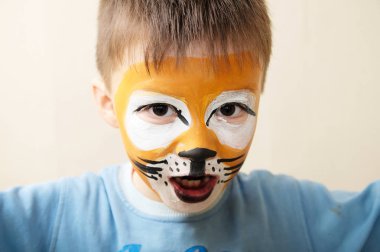 Çocuk boyama yüz. Çocuk sanatçı makyaj tarafından kaplan ya da vahşi aslan boyalı. Tiyatro performans için hazırlanıyor. Çocuk oyuncu oyun rolü. Kaplan maske yüz