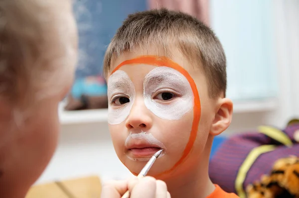 Maquiagem artista fazendo máscara de tigre para child.Children pintura facial. Menino pintado como tigre ou leão feroz. A preparar-se para o espectáculo teatral. Rapaz actor a interpretar papel. Cara de máscara tigre — Fotografia de Stock