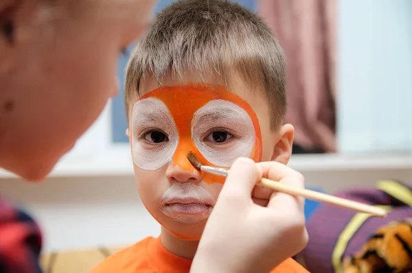 Maskenbildner bastelt Tigermaske für Kinderschminken. Junge als Tiger oder wilder Löwe gemalt. Vorbereitung auf die Theateraufführung. Junge Schauspieler in einer Rolle. Tigermaske — Stockfoto