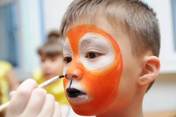 Maskenbildner bastelt Tigermaske für Kinderschminken. Junge als Tiger oder wilder Löwe gemalt. Vorbereitung auf die Theateraufführung. Junge Schauspieler in einer Rolle. Tigermaske — Stockfoto