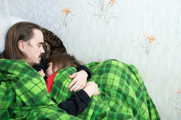 Padre e figlio dormono insieme sulla poltrona. Riposo in famiglia. Buona genitorialità, paternità. Papà e figlia avvolti nella coperta dormono abbastanza . — Foto Stock