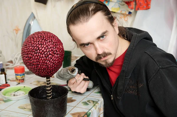 Homem artístico com pistola de cola fazendo árvore topiária artesanal de feijão, hobby de artesanato de decoração de casa — Fotografia de Stock