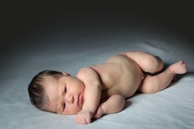 Yeni doğan bebek uyandırmak yatakta koyu arka plan, Asya bebek tam vücut portre üzerinde