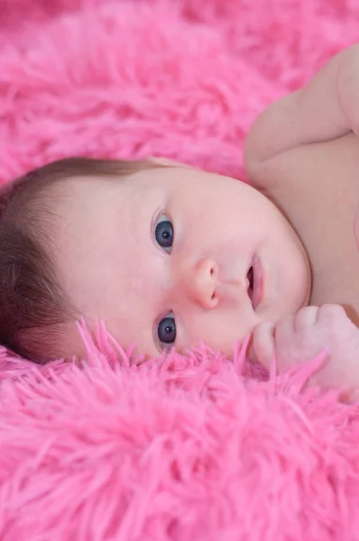 新生儿的画像，躺在粉红色的背景，看看相机的宝贝女儿 — 图库照片