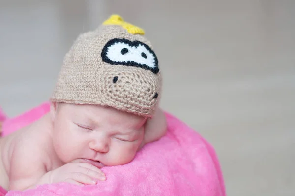 Cute happy newborn baby in dragon knitted cap sleeping in basket on pink blanket. Infant sleeping portrait. — Stock Photo, Image