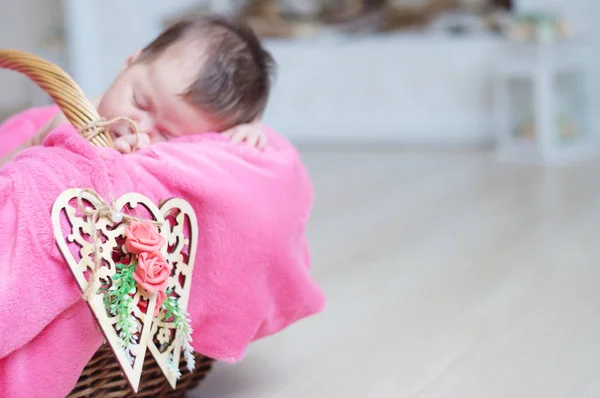 Houten hartjes op mand op focus, pasgeboren babymeisje slapen in de mand, liggen in roze deken, schattig kind, aankondiging dochterkaart ingericht — Stockfoto