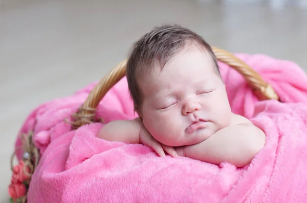 Újszülött alszik. Csecsemő baba lány rózsaszín takaró kosárban feküdt. Aranyos új gyermek-portré. — Stock Fotó