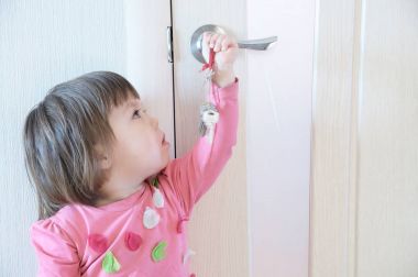 Kapı anahtar deliği ebeveynler tarafından unutulmuş tuşları ile oynayan çocuk. Çocuk güvenliği ve ev emniyet konsepti.