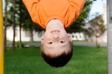 baş aşağı açık havada yatay çubuk jimnastiği ile oynayan çocuk. Çocuk Bahçesi, çocuk aktivite. Eğlenceli olan çocuğun. Etkin sağlıklı çocukluk kavramı