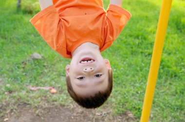 baş aşağı açık havada yatay çubuk jimnastiği ile oynayan çocuk. Çocuk Bahçesi, çocuk aktivite. Eğlenceli olan çocuğun. Etkin sağlıklı çocukluk kavramı