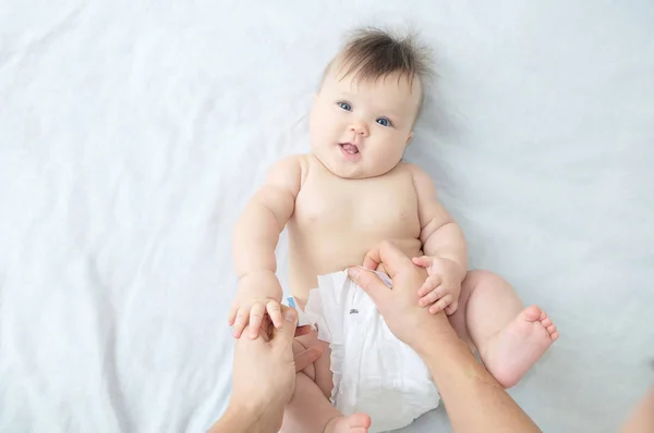 Cambiar pañal en la niña en la cama, cambiar pañal, cuidado diario, retrato sonriente del bebé — Foto de Stock