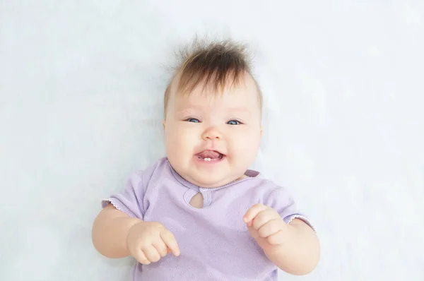 Gelukkig lachende baby baby portret kijken camera liggend op witte deken — Stockfoto