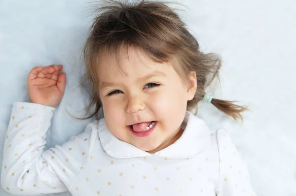 Felice sorridente bambina ritratto sdraiato sulla coperta bianca — Foto Stock