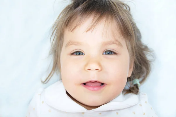 Happy souriant portrait de petite fille couché sur couverture blanche — Photo