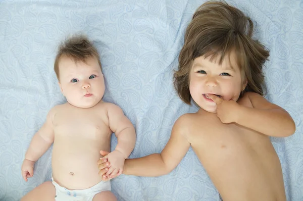 Irmãzinhas: filhinha e irmãzinha. Crianças felizes deitadas na cama — Fotografia de Stock