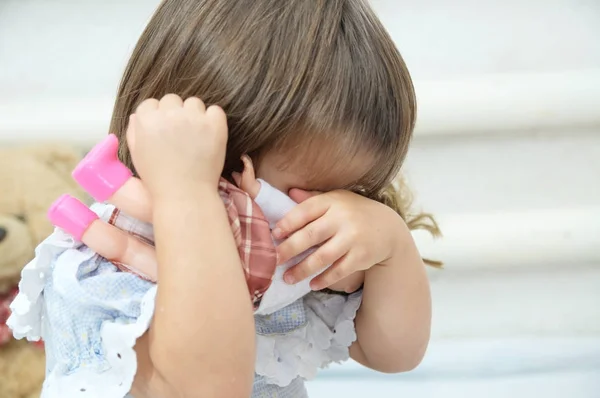 Bambina con bambola giocherellona che si nasconde piangendo — Foto Stock