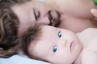 sleeping parent and baby waking up in the morning lying on bed together, happy family clipart