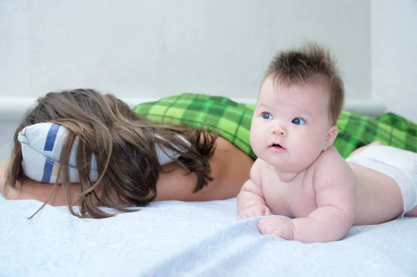 Sovande förälder och bebis vaknar på morgonen liggande på sängen tillsammans, lycklig familj — Stockfoto