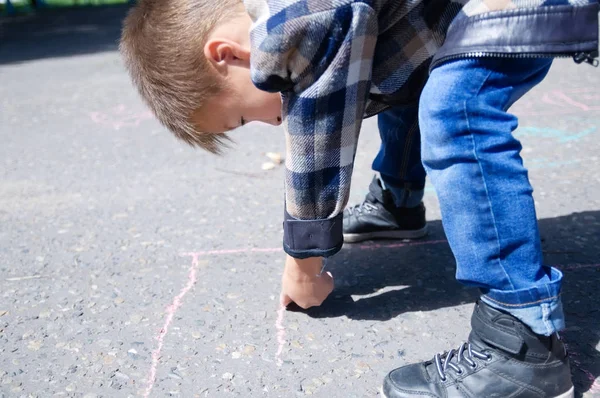 Kind zeichnet im Frühlingspark auf Asphalt. — Stockfoto