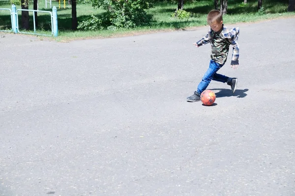 Jongen spelen voetbal, kind lopen met bal op asfalt, voetbal teamspeler, opleiding buiten, actieve levensstijl, sport achtergrond — Stockfoto