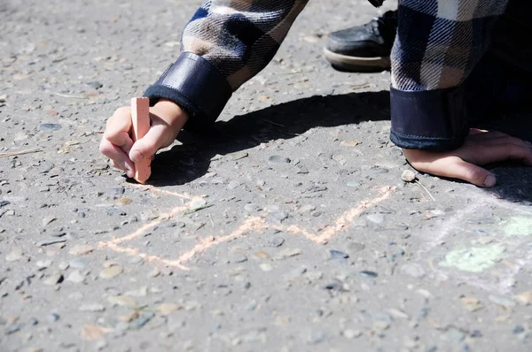 Child drawing on asphalt in spring, boy paint crayons in the park