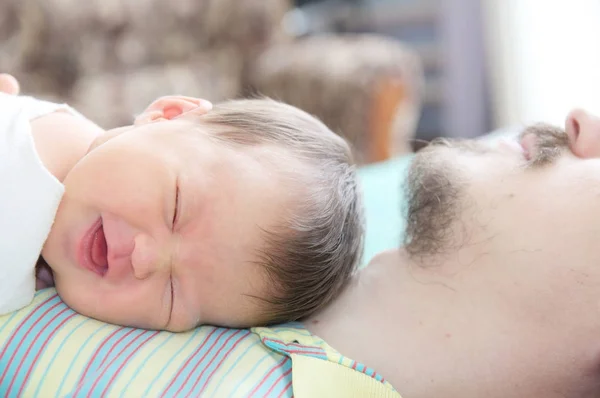 Sleeping newborn baby happy smiling portrait lying on father — Stock Photo, Image