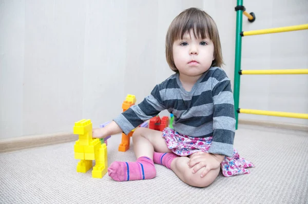 Little girl play with dinosaur figurines made by plastic constructor block kit toys — Stock Photo, Image