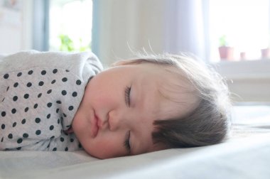 Bebek portre yakın kadar gündüz güneş ışınları, sağlık yatakta üzerinde dinlenme uyku. Sevimli küçük kız uyku
