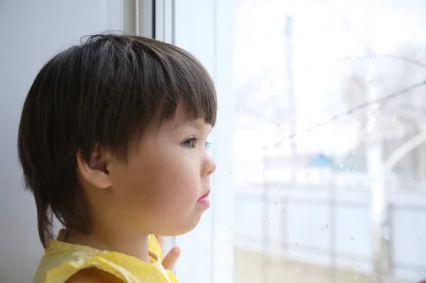 小女孩望着窗外渴望阳光 好奇心 Childness 雨天坐在家里的孩子 — 图库照片