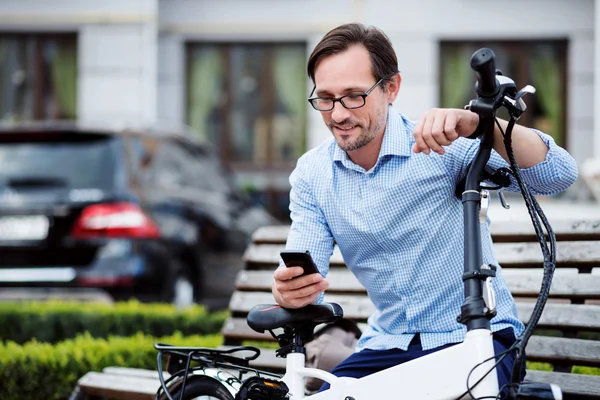 Bel homme bespectacled en utilisant un téléphone portable . — Photo