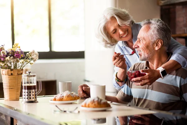 Nyugdíjas férfi és nő reggelizik a konyhában — Stock Fotó