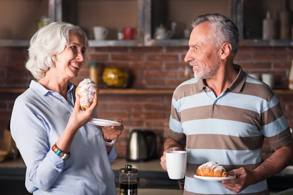 Personas mayores tomando café y cruasán juntas en la cocina — Foto de Stock