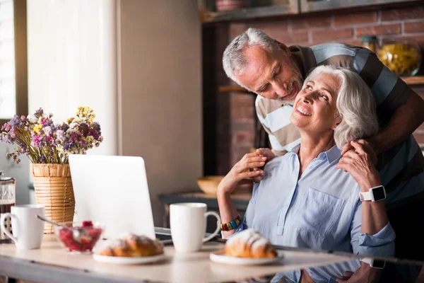 Nice looking old man embracing his wife from her back — Stock Photo, Image