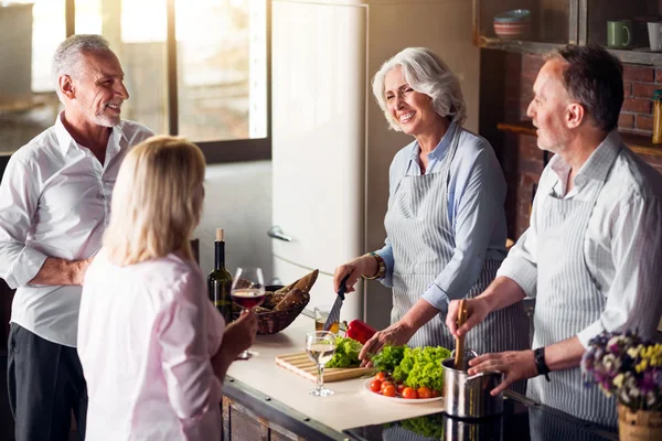 Quatre gentilles personnes âgées réunies autour de la table dans la cuisine — Photo