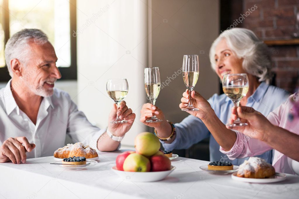 Four glasses of wine being raised at the house party