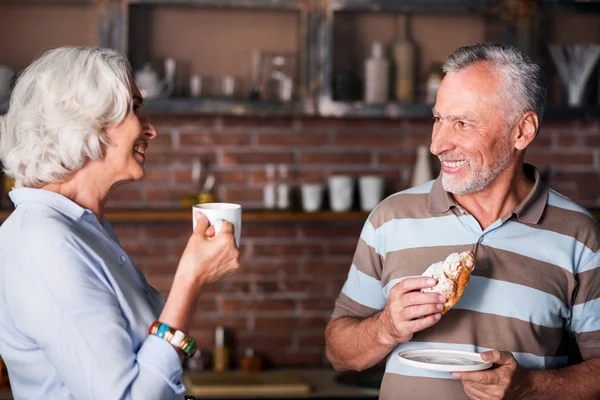 Hombre y mujer de sesenta años contando chistes en la cocina — Foto de Stock