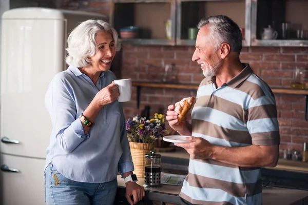 Feliz pareja de ancianos sonriéndose mientras beben café — Foto de Stock