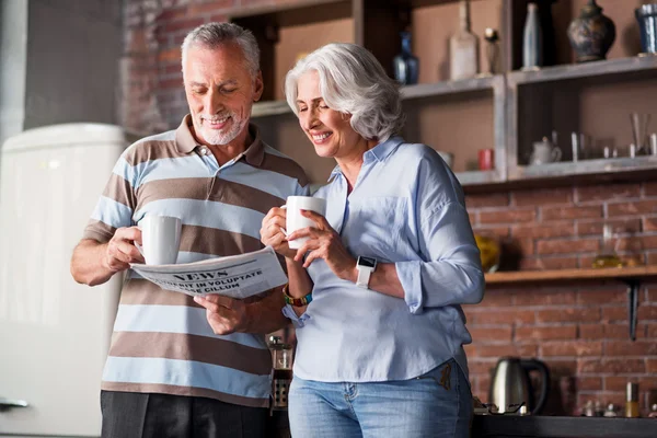 Glückliches nobles Paar in den Sechzigern, das in der Küche lacht — Stockfoto