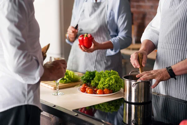 Les gens se sont réunis autour de la table de cuisine pour cuisiner et discuter — Photo